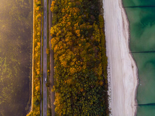 drone view of a colourful autumn sunset over the hel peninsula, the baltic sea and the gulf of puck; colourful autumn leaves on the trees - obrazy, fototapety, plakaty