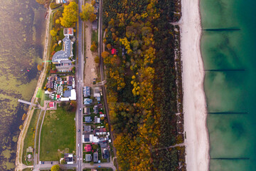 drone view of colourful autumn sunset over the village by the baltic sea, chalupy, poland; colourful autumn trees over the sea, sunset over the hel peninsula, baltic sea and puck bay
