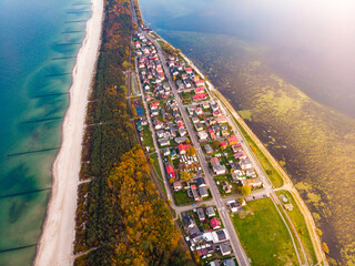 drone view of colourful autumn sunset over the village by the baltic sea, chalupy, poland; colourful autumn trees over the sea, sunset over the hel peninsula, baltic sea and puck bay - obrazy, fototapety, plakaty