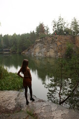 Fototapeta na wymiar The Great Korostyshiv Canyon. The girl stands in the rain and looks at the water. There are many conifers around