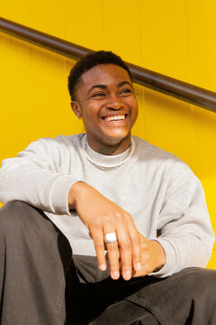 A portrait of a black trans masculine person smiling.