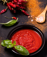 on a textured black background, some ingredients, garlic and dried chili, fresh basil and bowl with...