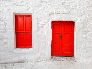 Door and window with closed shutters of red color in a house with white walls, Turkish building, national colors..