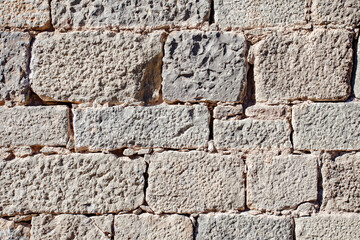 Wall old made of beige stone blocks, close-up exterior view of surface of rectangular stone, masonry