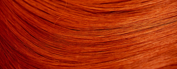 Red hair close-up as a background. Women's long orange hair. Beautifully styled wavy shiny curls....