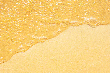 water runs over fine sand in close-up.