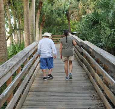 Old father and middle aged daughter walking together.