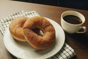 Freshly made donuts on the breakfast table with black coffee - 541787832