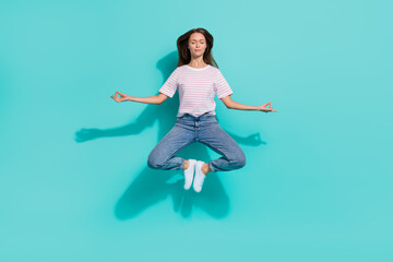 Full size photo of calm relaxed woman with brown hair wear striped t-shirt levitating in yoga pose isolated on teal color background