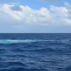 Deep blue wavy ocean on a sunny day with clouds in the sky