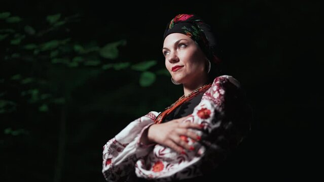 Beautiful woman in traditional ukrainian handkerchief, necklace and costume on night forest background. Lady in national dress - vyshyvanka, ancient coral beads. Concept of ethnic style, traditions