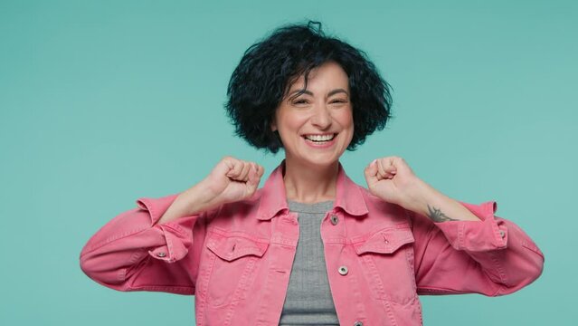 Slow motion excited 40s mature woman with curly hair screaming loud. Woman trying to get attention. Concept of sales, promotion, valuable offer. Passionate happy lady on teal blue studio background 4K