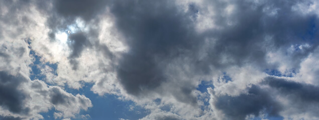 Obraz premium Sun shines through clouds on overcast sky - bright disc visible