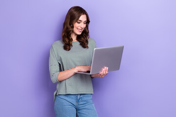 Photo of concentrated pretty lady wear trendy clothes use gadget netbook write friends read news isolated on purple color background