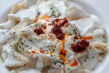 Turkish traditional food ravioli with yoghurt and tomato sauce in plate, manti
