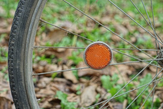 side old plastic bicycle reflector orange color on the spokes of a bicycle retro wheel on the street during the day