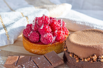 Fresh raspberry and chocolate tarts on the kitchen table background close up.
