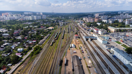 City, locality. Railway station. Passenger and cargo transportation. Residential area on a sunny summer day. Apartment buildings, high-rise buildings. The view from the drone, from above.