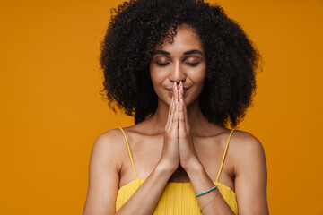 Young beautiful curly woman with closed eyes and folded hands
