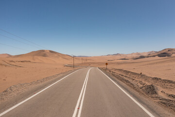 A road, high tension cables and a traffic signal in the middle of the atacama desert near the city of Copiapó, Chile