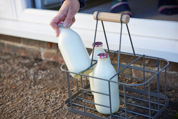 Fototapeta na wymiar Person Picking Up Bottle Of Milk From House Door Step