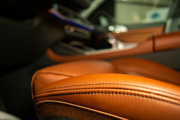 Soft focus close up of an orange leather driver's seat