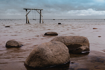 Seascape view with rocks and swing in the water in cloudy overcast day. High quality photo
