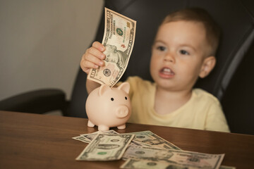 Smart happy child boy putting in piggy bank dollar banknote. Saving money in a piggy bank, learning about saving. Money, finances, insurance, and people concept