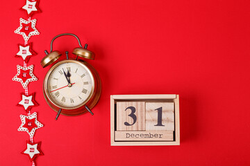 Christmas garland, gold-colored clock and December 31 calendar on a red background