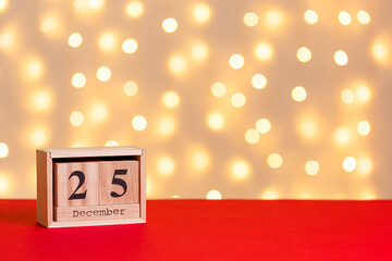christmas wooden calendar 25 december on red background and lights background