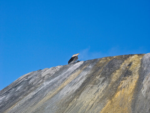 A single dump truck dumps rock on a huge pile