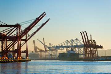 Fototapeta na wymiar Harbor cranes unloading a container ship at port