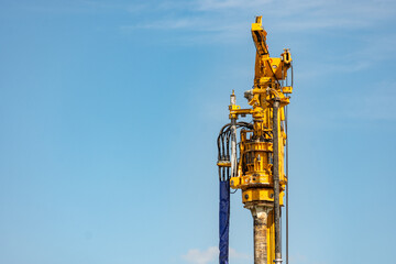 Fototapeta na wymiar Big yellow mechanical deep drilling machine against clear blue sky
