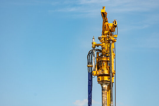 Big yellow mechanical deep drilling machine against clear blue sky