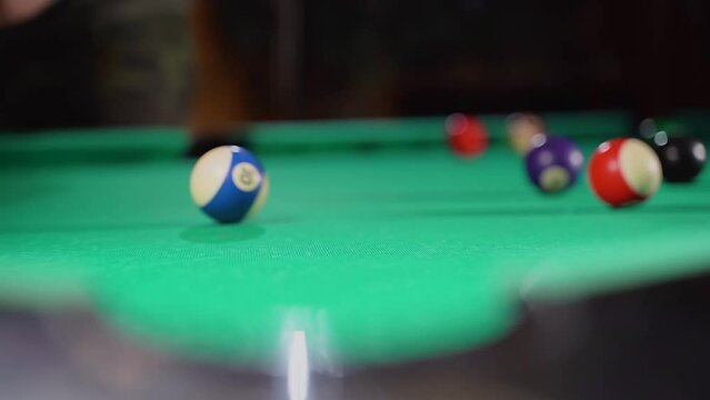 man hammers a ball into a billiard pocket