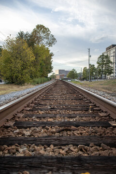 Long Railroad Train Tracks with Buildings and a Pretty Sky in the background