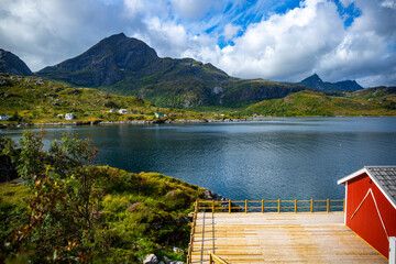 the harsh landscape of the norwegian fjords on the Lofoten islands, small houses by the sea with huge mountains above them