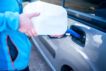 Pouring adblue to the car. Male driver adding Diesel exhaust fluid to his car.