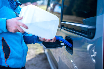 Pouring adblue to the car. Male driver adding Diesel exhaust fluid to his car.