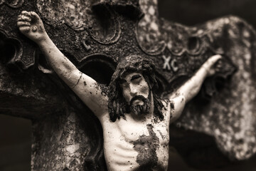 Ancient stone sculpture of Jesus Christ, crucified on a stone cross