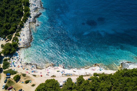 Aerial shot of a beautiful beach surrounded by greenery in Premantura, Croatia