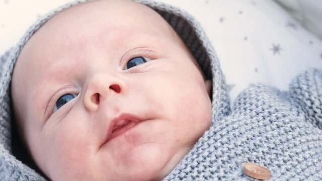 4k footage video. Close up newborn baby child lying in baby carriage stroller buggy having fun playing, dressed knitted sweater, smiling infant. Outside walking in pushchair, fresh air
