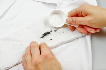 a woman's hand holds a stain remover to remove a dirty stain from clothes. concept of washing and cleaning