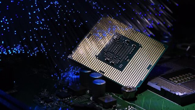 Detail of a modern CPU on a PC motherboard illuminated by a bunch of colored fiber optics. Zoom out