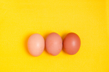 Brown chicken eggs on yellow background with copy space. Easter and healthy eating.