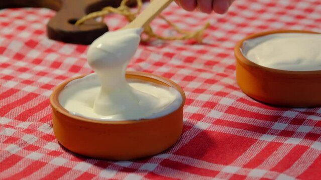 With spoon fresh yogurt close up.Mixing yogurt in bowl.4K UHD video
