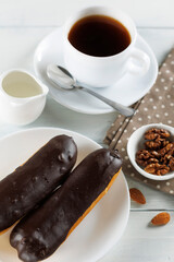 Chocolate eclairs with coffee and milk. Chocolate eclairs with coffee and milk. Traditional sweet breakfast. Cafe menu