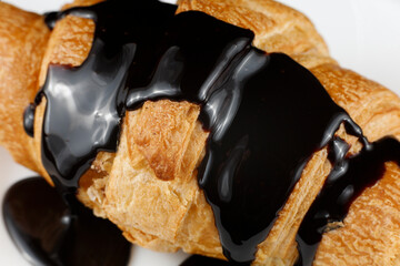 Chocolate poured on croissant close-up. Chocolate with a croissant on a plate.
