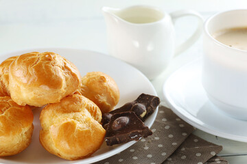 eclairs with chocolate, cappuccino and milk. Sweet breakfast.