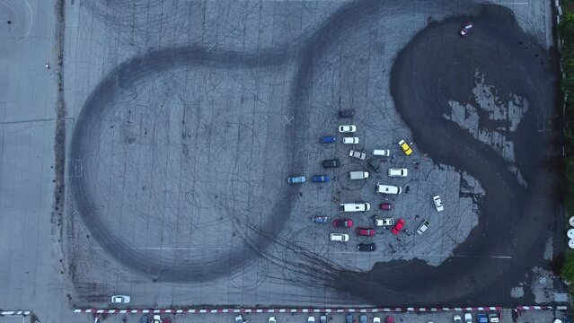 4k Aerial view of lot of cars drift on ground in modern city irrl. Above pic of transport rides on asphalt site and trains or competes in open air. Creative operator uses flying drone and films